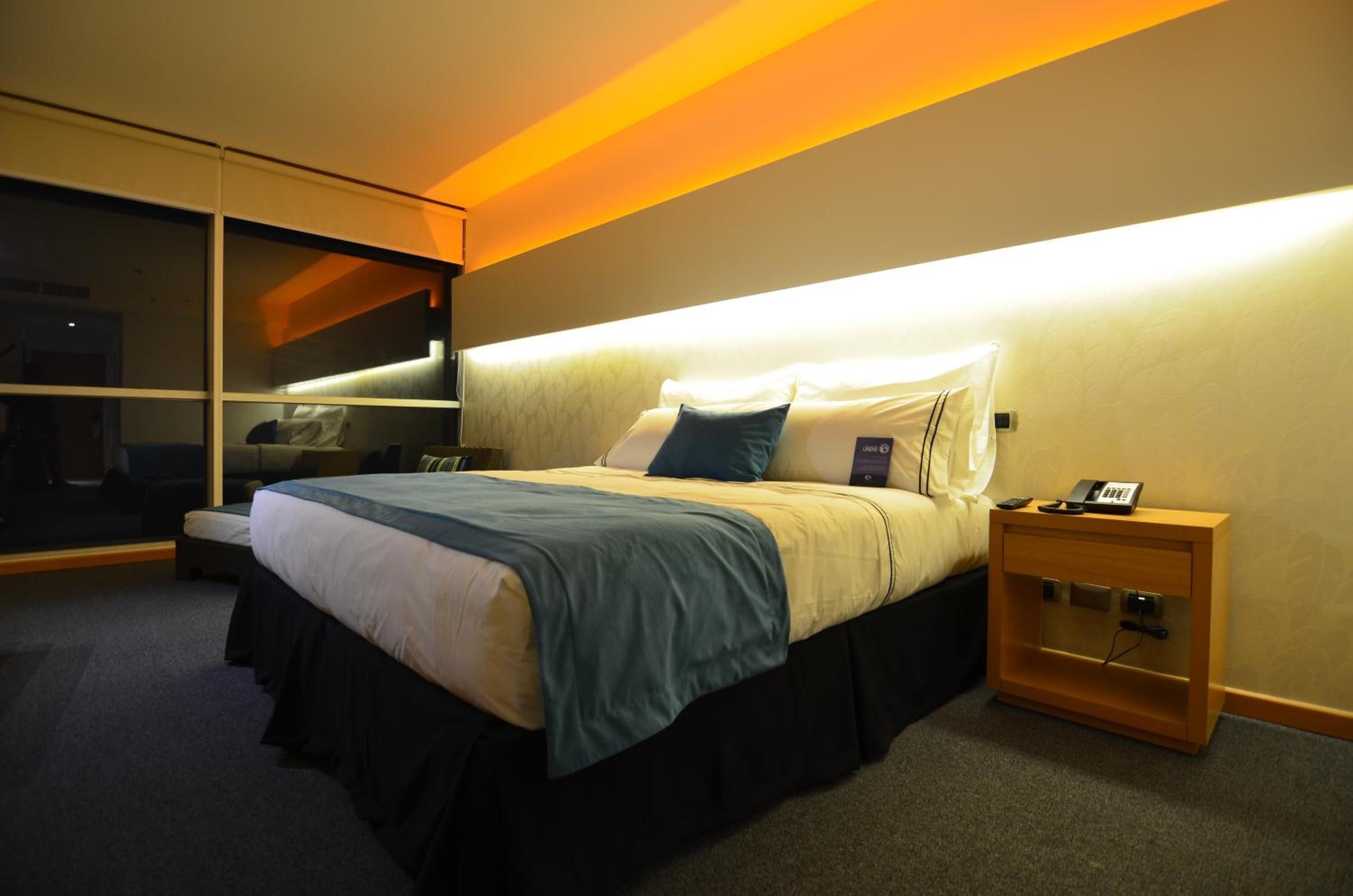 A modern bedroom with a large bed, bedside table, and a sliding door closet.