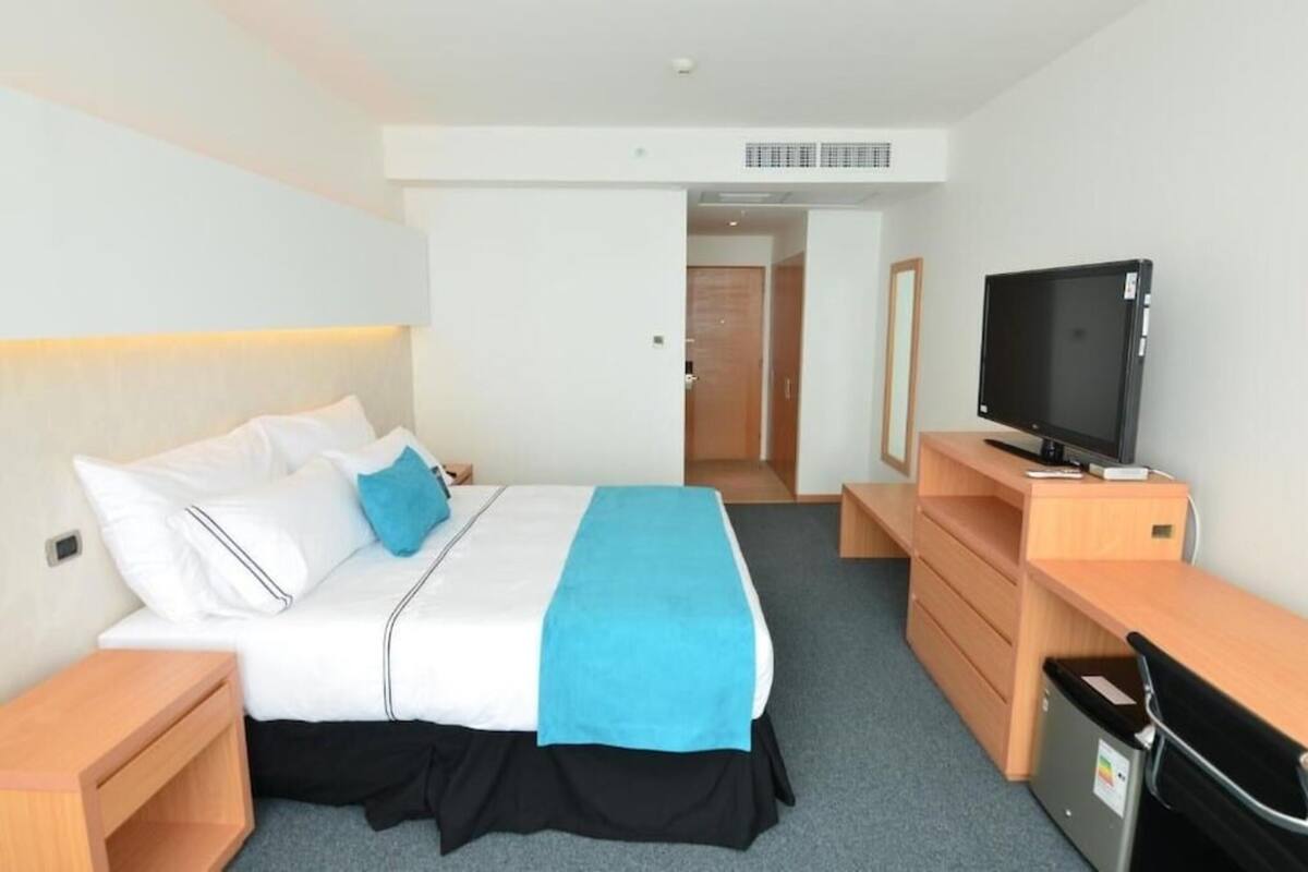 Une chambre d’hôtel avec un lit, une télévision, un bureau et une chaise.