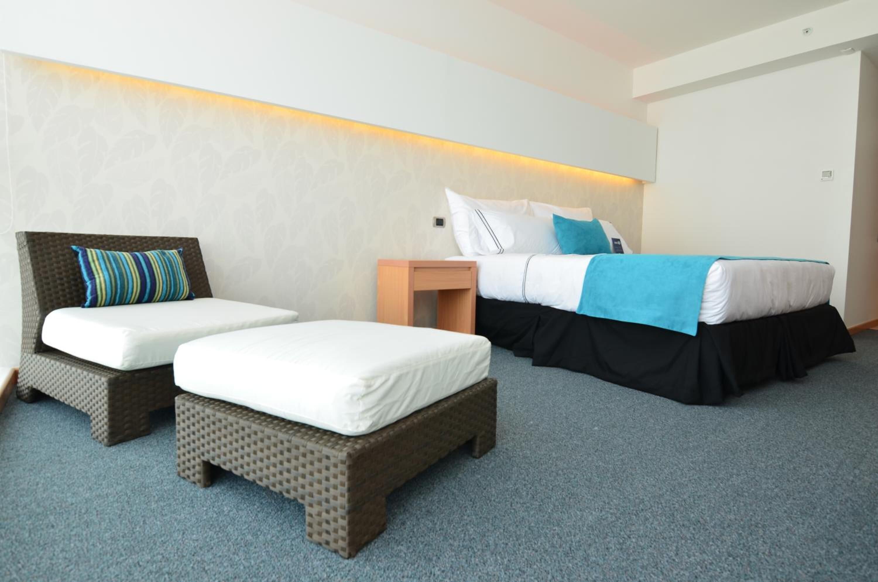A hotel room with two single beds, a small bedside table, and a large bed.