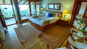 Hotelkamer met een bed, een bureau, een stoel, een klein tafeltje met een lamp en uitzicht op buiten.