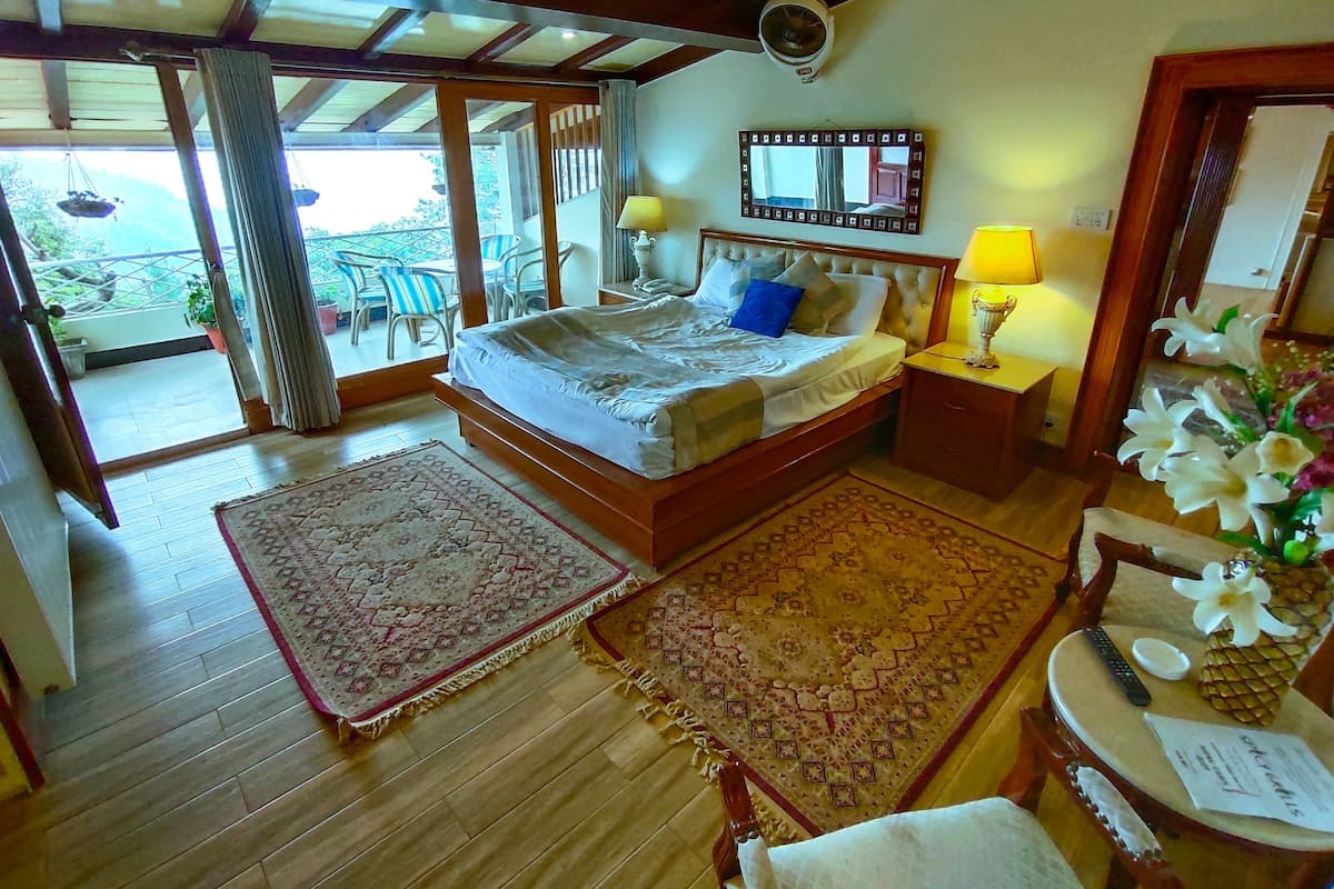 Une chambre d’hôtel comprenant un lit, un bureau, une chaise, une petite table avec une lampe et une vue sur l’extérieur.