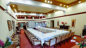 Een vergaderzaal met een lange tafel, stoelen, een whiteboard en een projectorscherm.