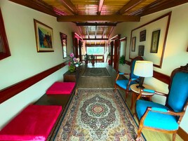 Un pasillo con alfombra estampada, bancos de madera y sillas con cojines azules.