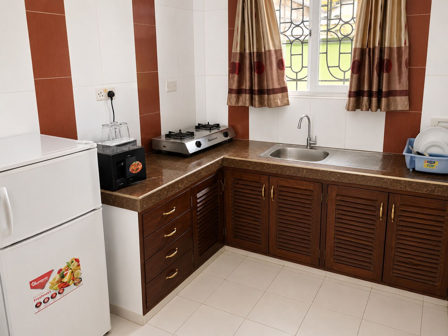 Una cocina con refrigerador, estufa, lavamanos y gabinetes de madera.