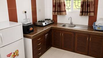 Una cocina con refrigerador, estufa, lavamanos y gabinetes de madera.