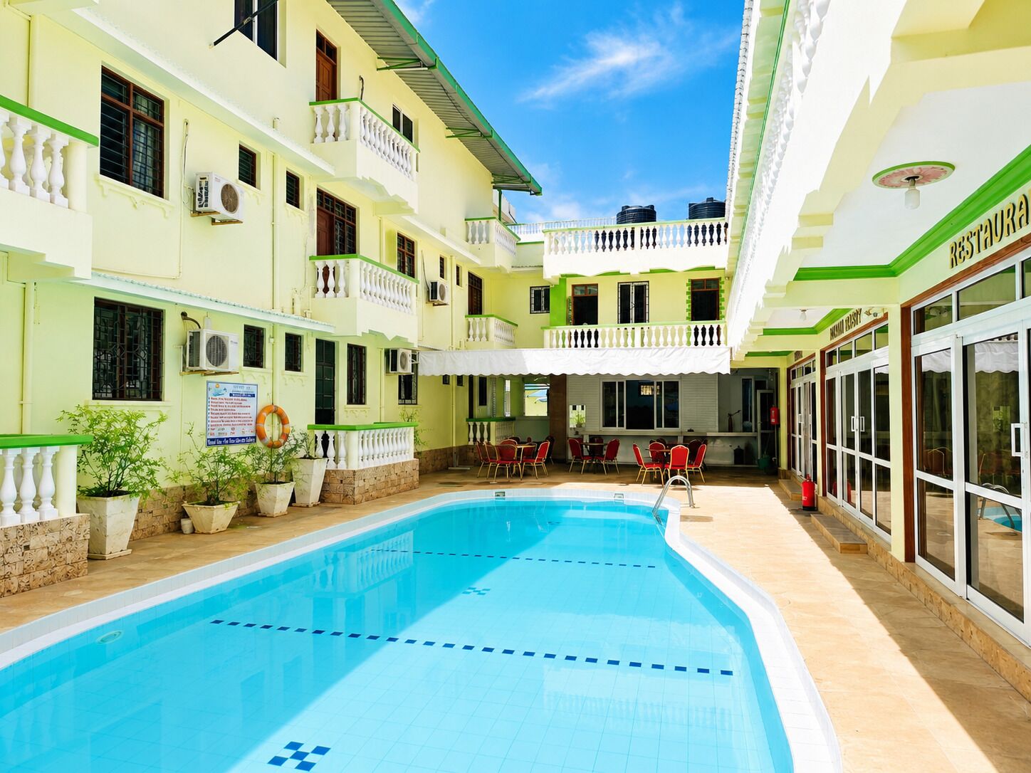 A hotel with a swimming pool, multiple balconies, and a restaurant.