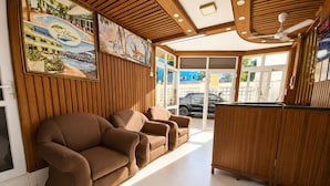 Un espace d’accueil avec des panneaux de bois, un comptoir de réception et un coin salon avec des canapés.