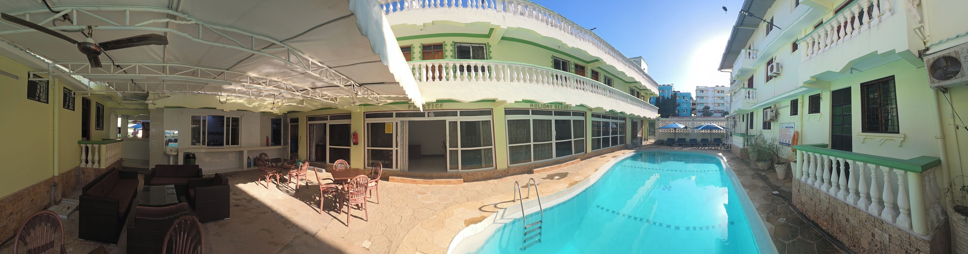 A poolside area with outdoor seating, a pool, and a building with a balcony.