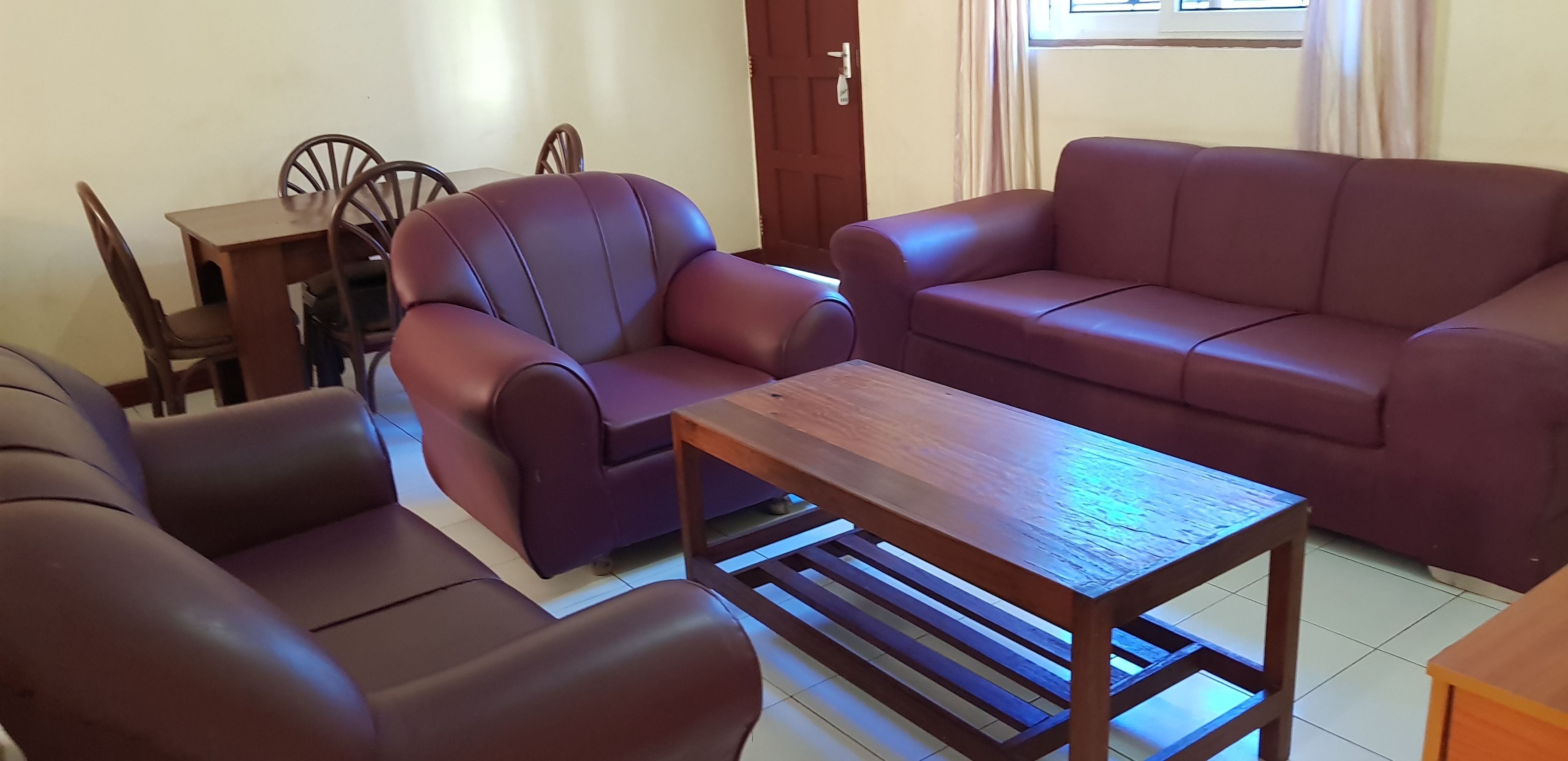 A living room with a brown leather sofa, a matching armchair, and a wooden coffee table.