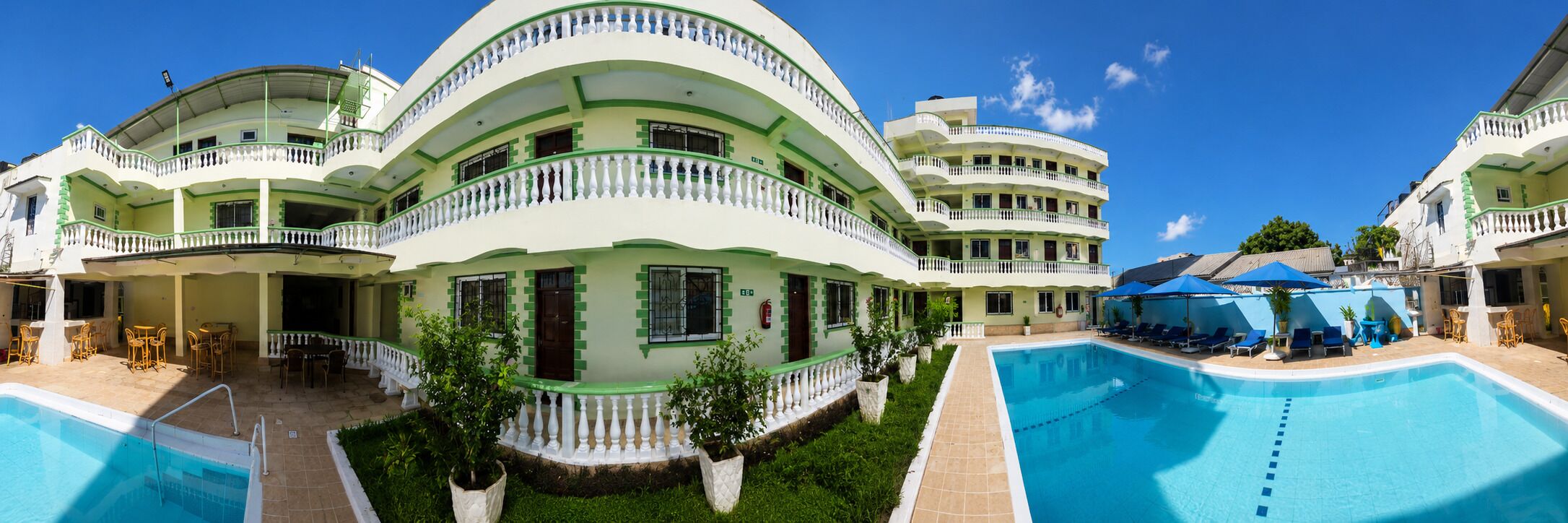 Un hotel su più piani con piscina, area salotto esterna e giardino curato.