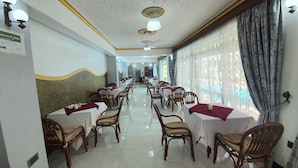Un espace repas avec des tables et des chaises, un plafond agrémenté d’éléments décoratifs et une vue par la fenêtre.