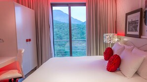Habitación de hotel con cama, escritorio y vista a un paisaje montañoso.