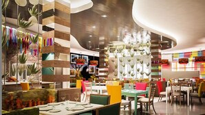 Un restaurante moderno con diversas opciones de asientos, incluyendo mesas y cabinas, y una decoración interior colorida.