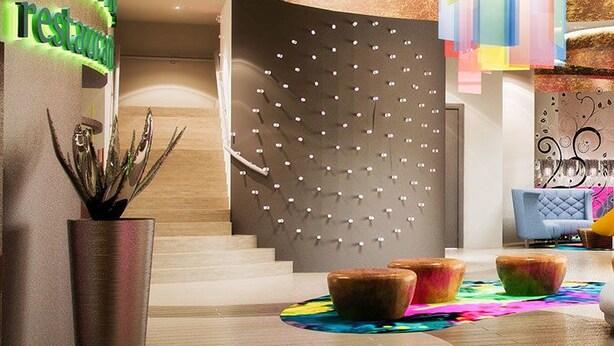 Un moderno vestíbulo de hotel con una recepción, decoración colorida y una zona de estar original.
