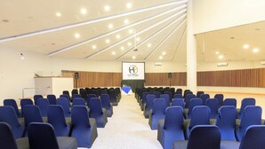 A conference room with rows of blue chairs, a podium, and a screen displaying 'HOTEL FRONTERA'. - Hotel Frontera Plaza (Temuco)