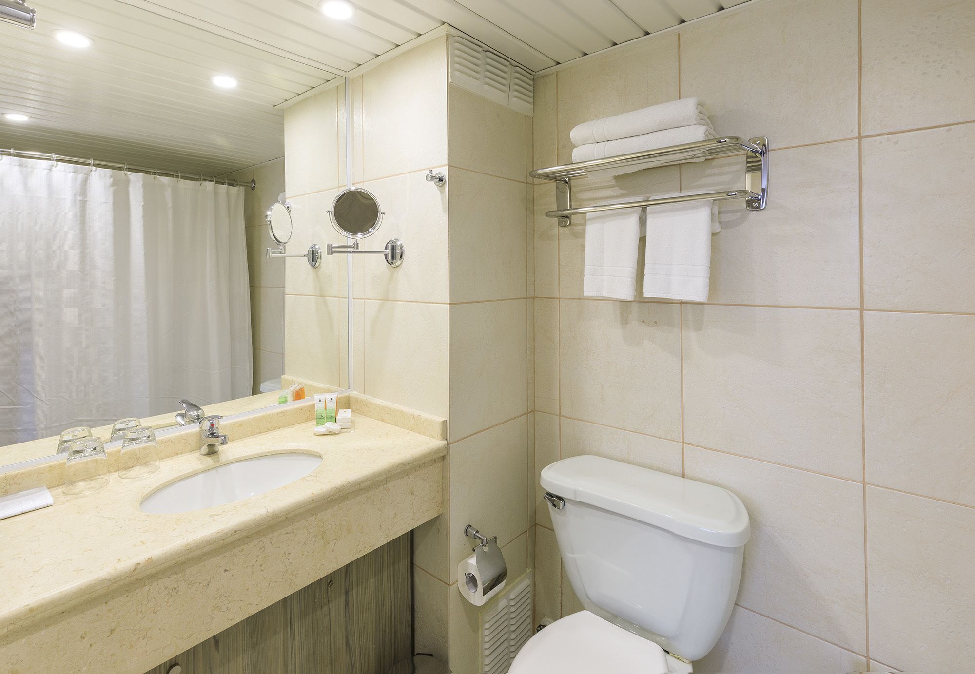 A bathroom with two sinks, a toilet, a towel rack, and a mirror.