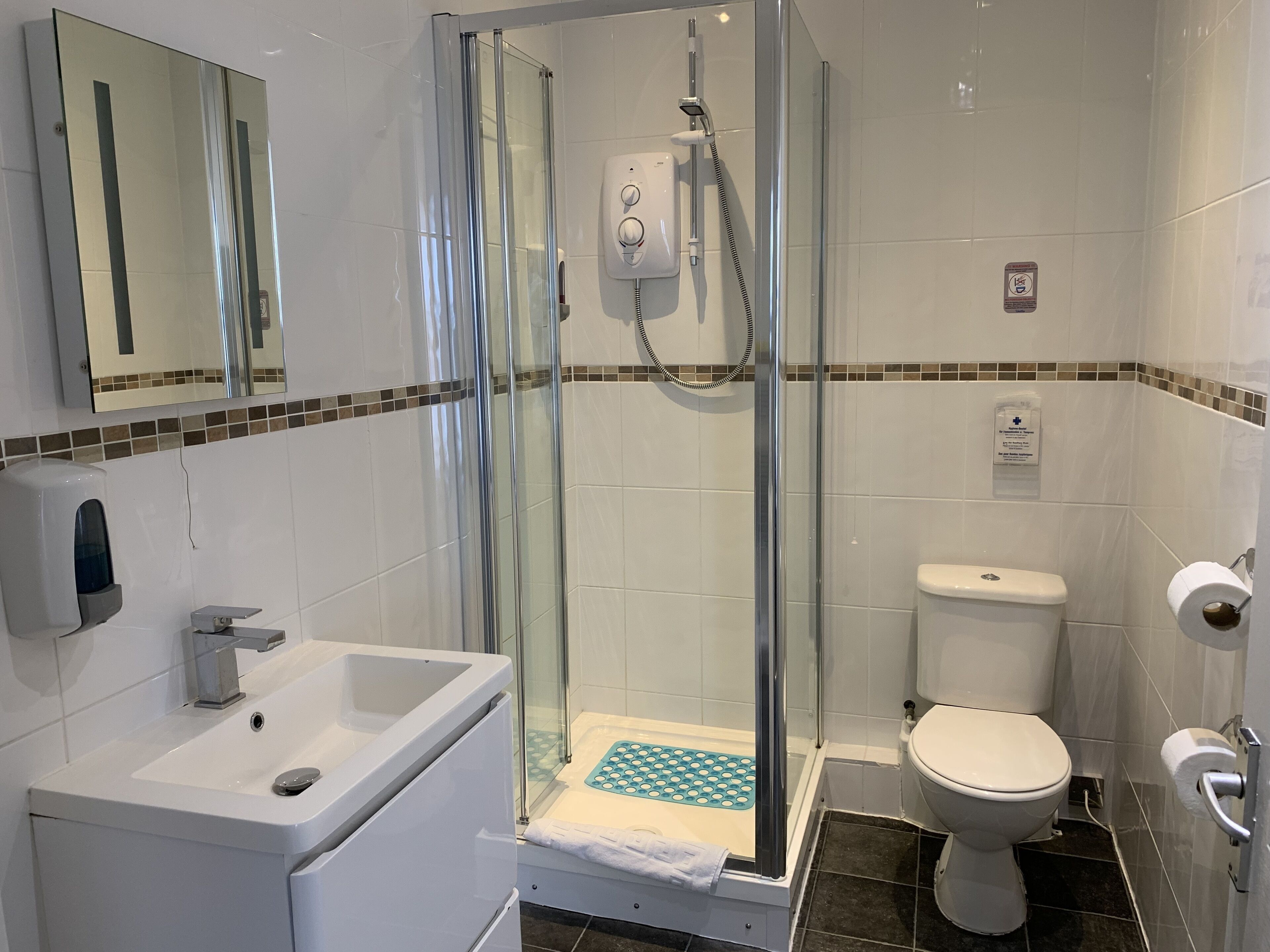 A modern bathroom with a glass-enclosed shower, a white sink, and a toilet.