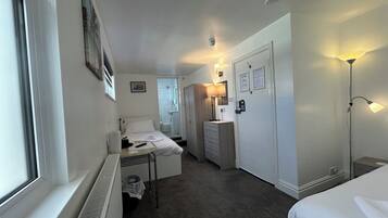 A hotel room with a bed, bedside table, lamp, and a view of the bathroom.
