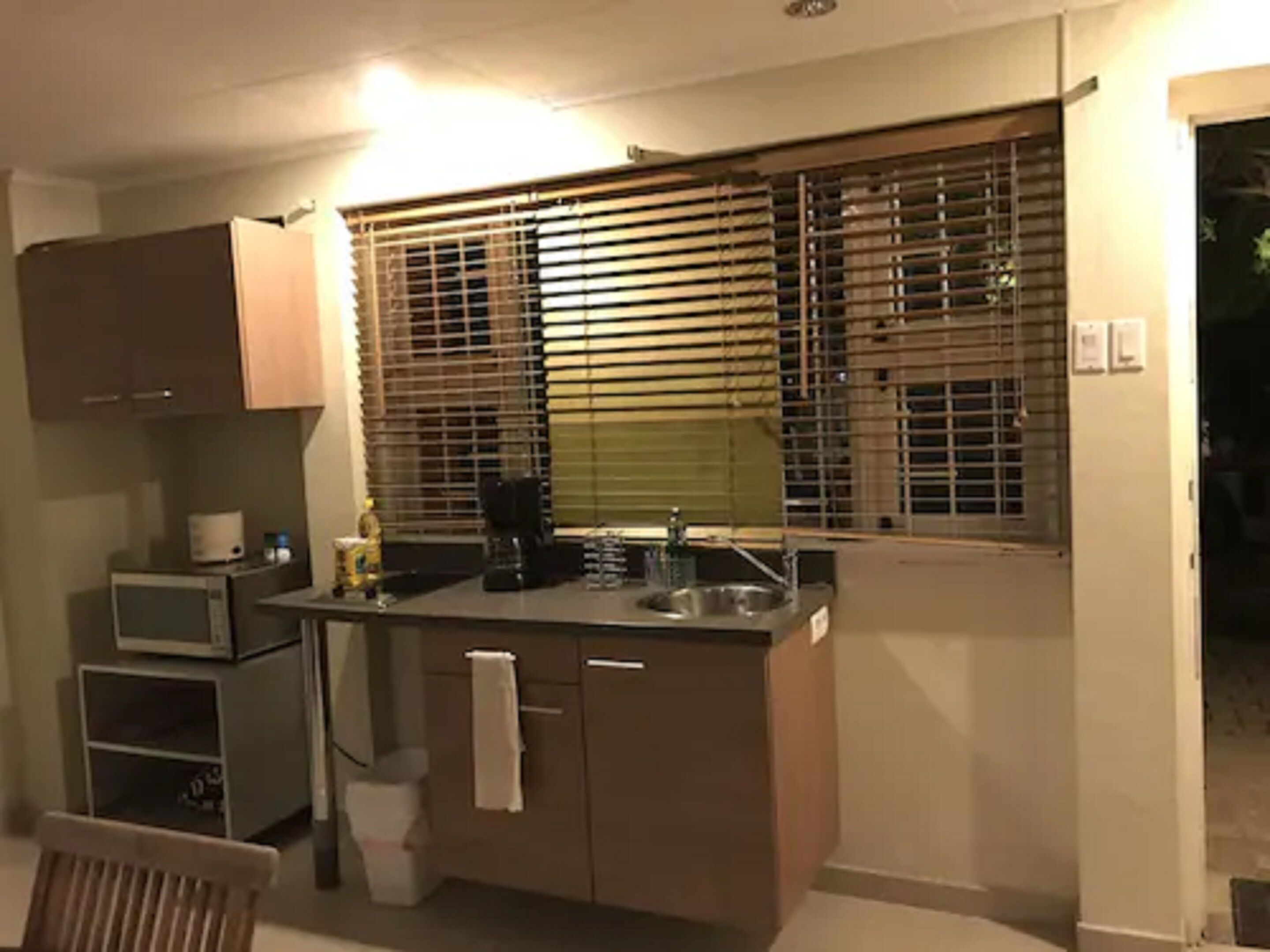 Une cuisine de taille réduite, équipée d’un four à micro-ondes, d’un évier et de meubles de rangement en bois.