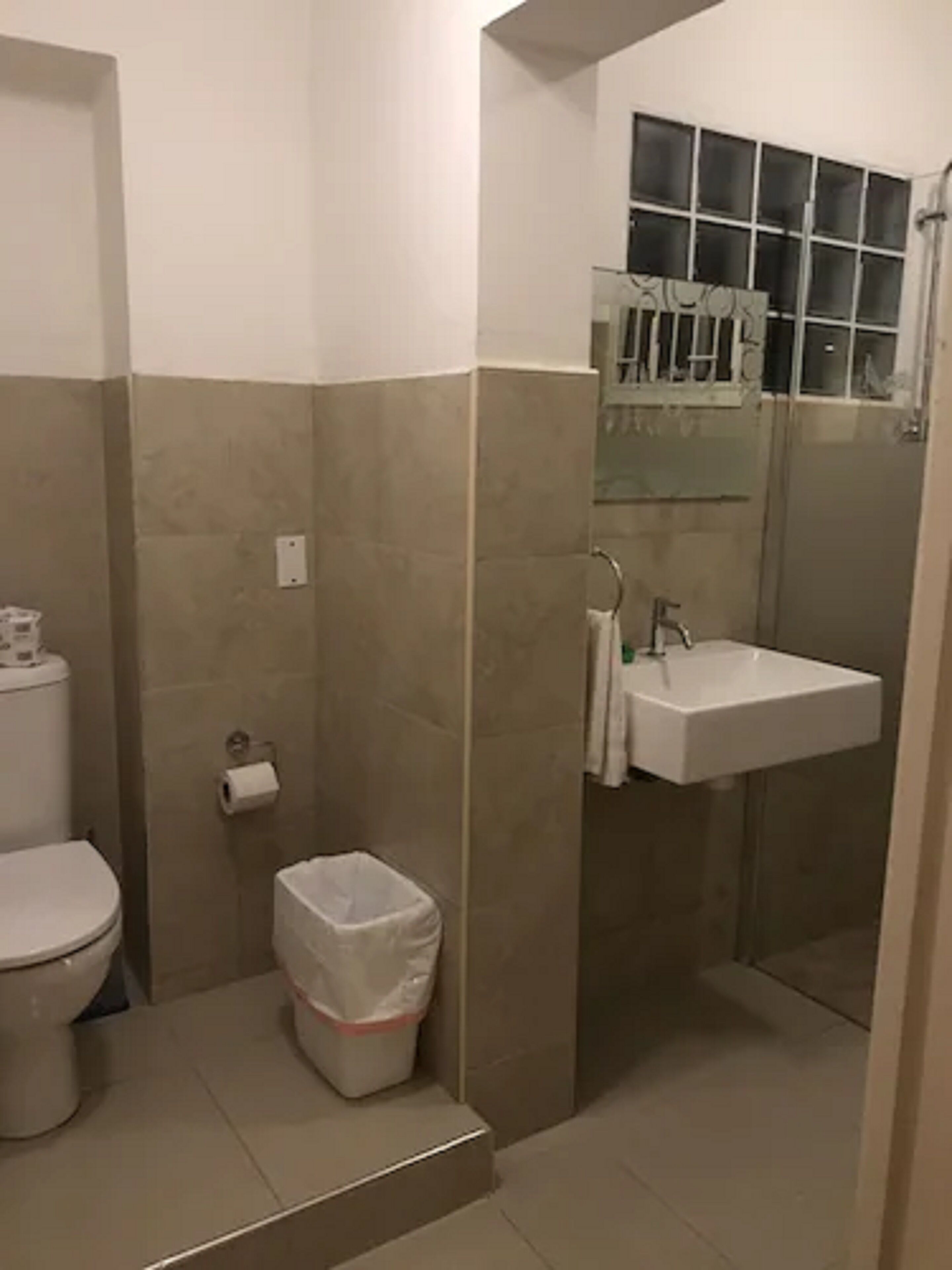 Un baño con inodoro, lavamanos y zona de ducha.
