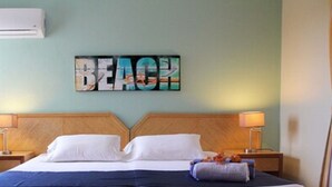 A hotel room with a bed, two bedside tables, and a wall-mounted artwork spelling "BEACH". - O Casarao Guesthouse (Willemstad)