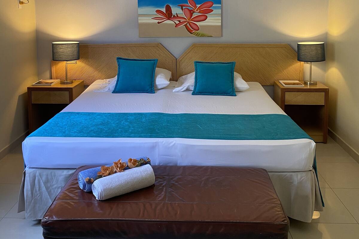 Een hotelkamer met een bed, twee bedlampen, een plafondventilator en een schilderij aan de muur.
