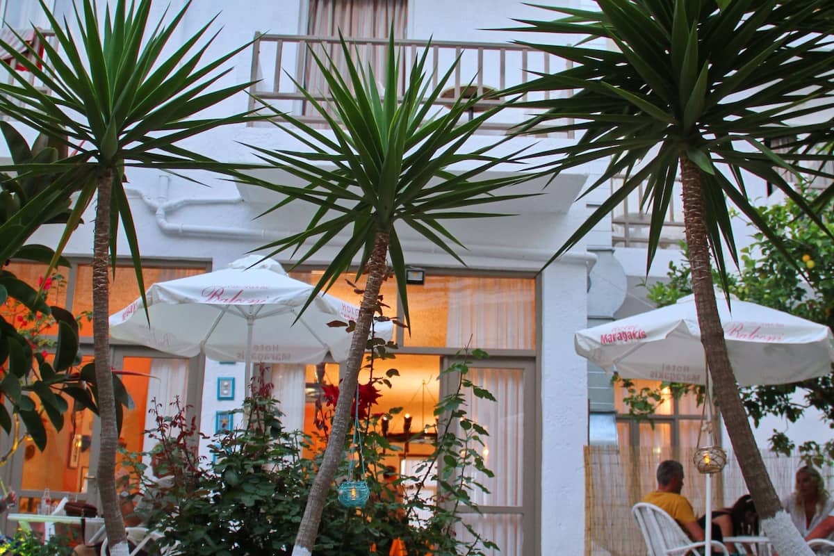 A courtyard with palm trees, outdoor seating, and a building with balconies.