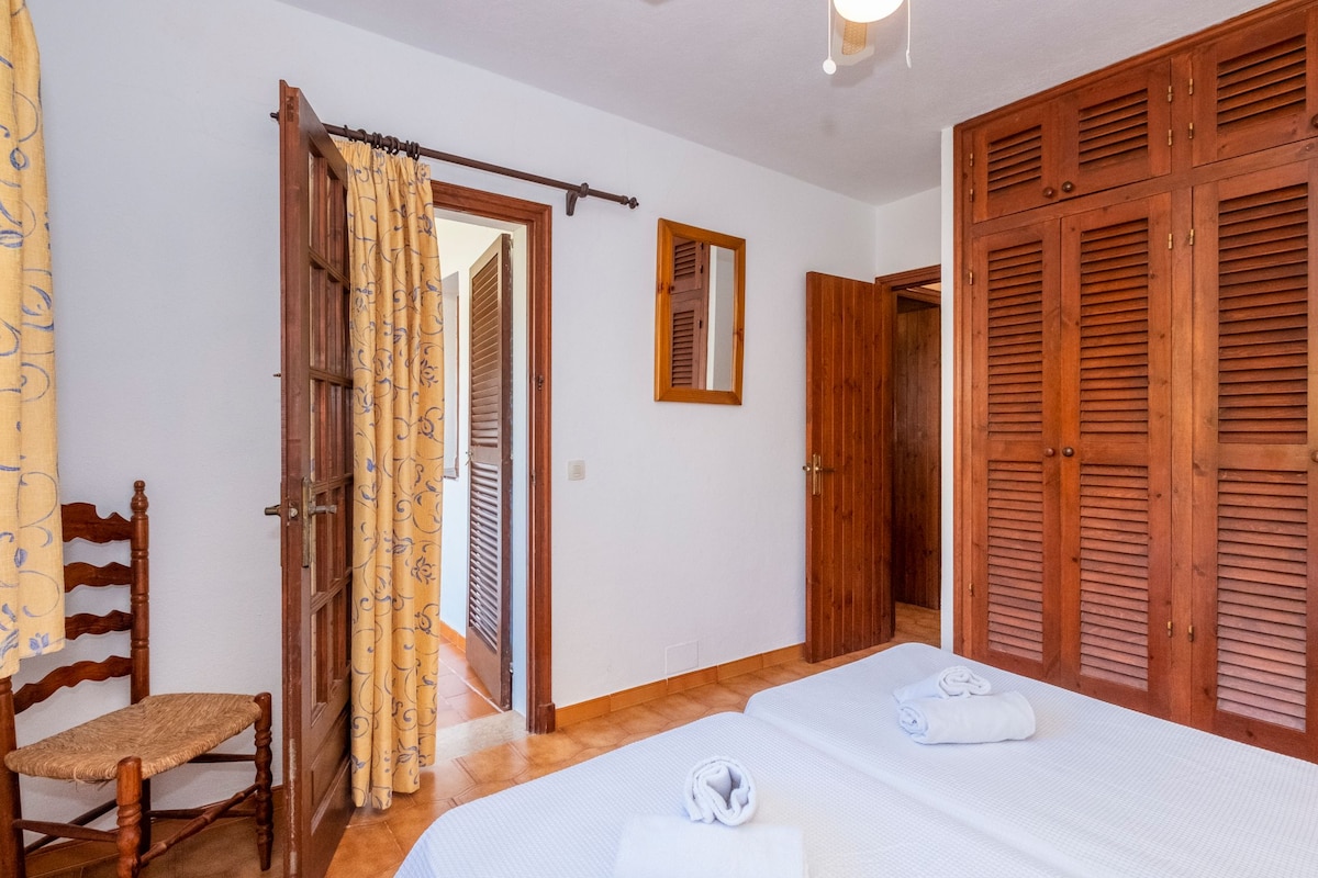 Un dormitorio con cama, armario de madera, una silla y un espejo.
