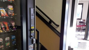 A vending machine with snacks and drinks, located near a staircase in a building.