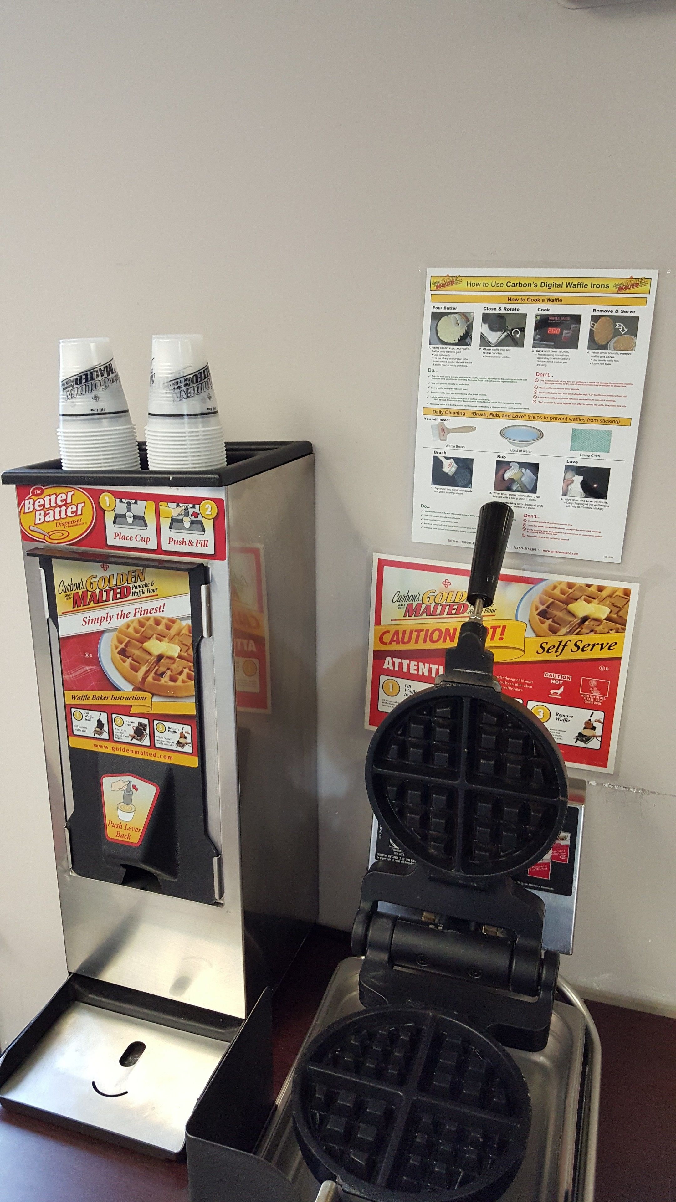 Un gaufrier et un appareil à gaufres, avec des affiches explicatives accrochées au mur.