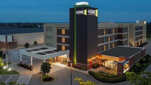 A hotel with a prominent sign reading "HOME 2 HOME" and a covered parking area.