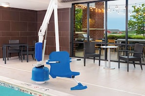 Relax by the pool with a casual dining or relaxation space featuring a blue chair, wicker chairs, and a small table.