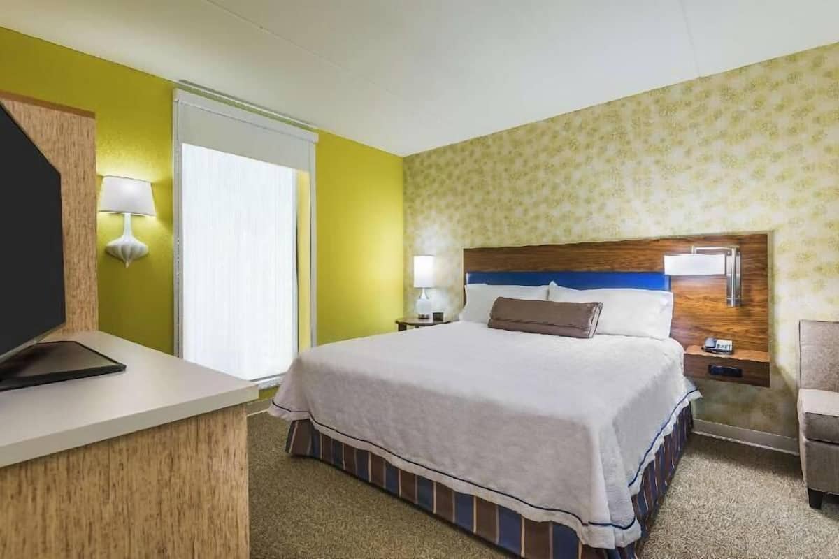 Ett hotellrum med en säng, sängbord, ett skrivbord och en stol.