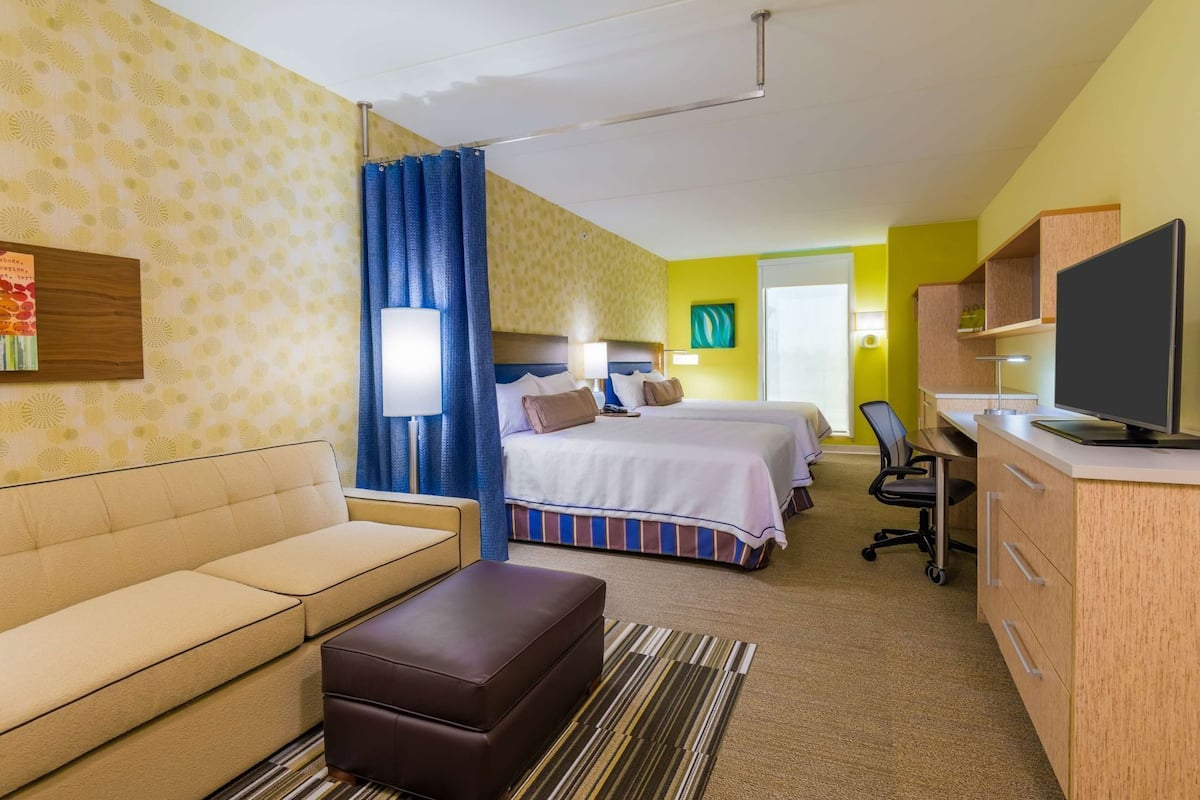 Ett hotellrum med en soffa, en säng, ett skrivbord med en dator och en tv.