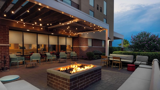 An outdoor patio with a fire pit, seating, and string lights.