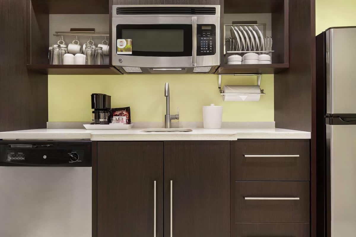 A kitchen with a built-in microwave, a coffee maker, and a dish rack.