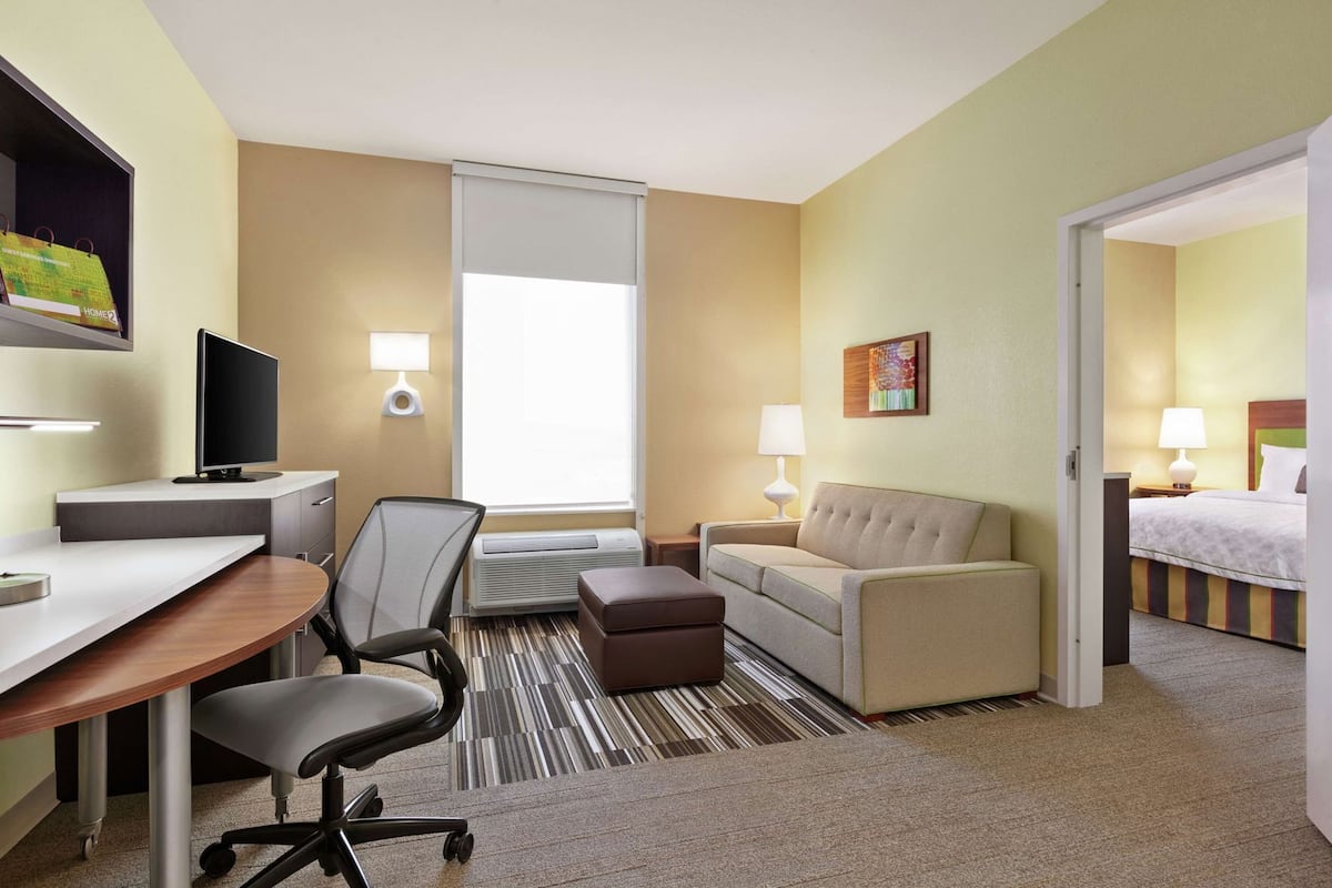 A hotel room with a desk, chair, sofa, and bed.