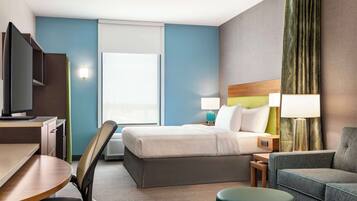 Habitación de hotel con cama, escritorio, silla, sofá y televisor.