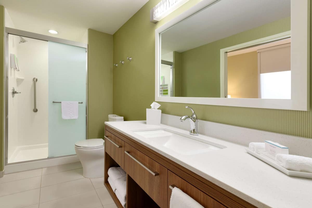 A modern bathroom with a glass shower enclosure, a white sink, and a large mirror.