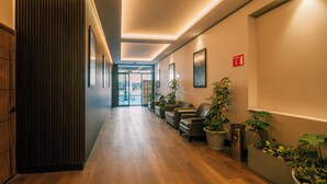 Un moderno vestíbulo de hotel con suelo de madera, asientos de cuero y plantas en macetas.