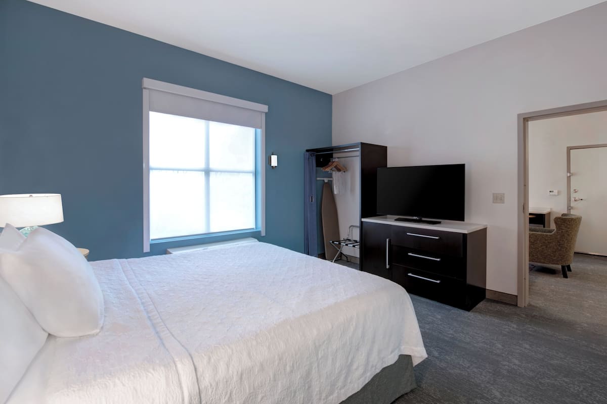 A hotel room with a bed, a TV, a desk, and a chair.