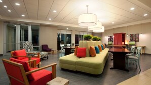 A modern lobby with seating areas, a reception desk, and a large window.