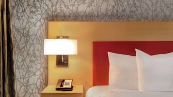 Una habitación de hotel con cama, lámpara de noche, teléfono y mesita de noche.