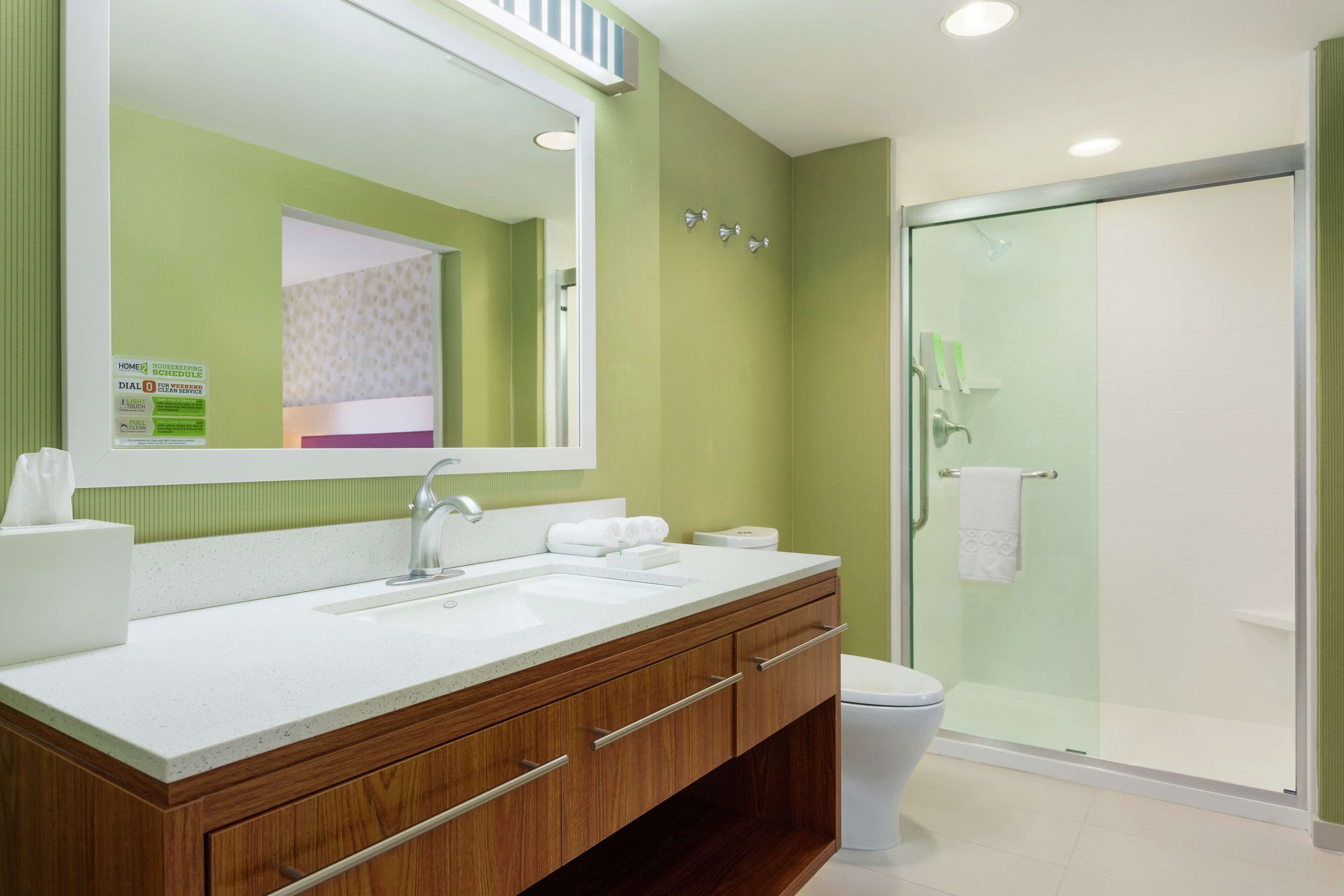 A modern bathroom with a double sink vanity, a glass shower enclosure, and a visible toilet.