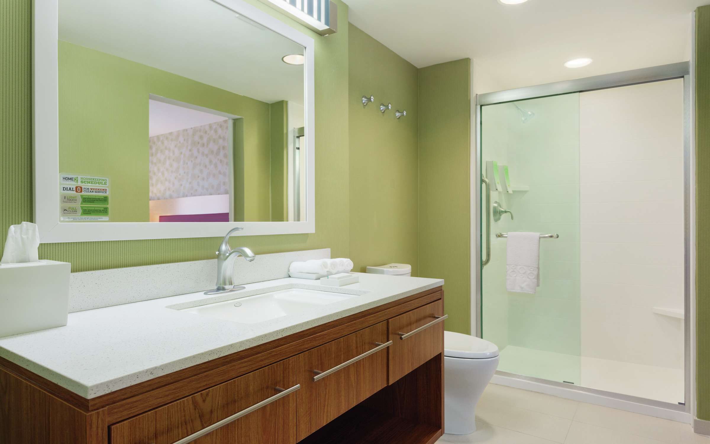A modern bathroom with a large mirror, a sink, and a shower area.