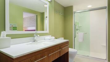 A modern bathroom with a large mirror, a sink, and a shower area.