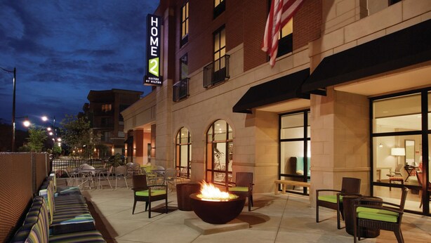 A hotel exterior with outdoor seating, a fire feature, and a large American flag.