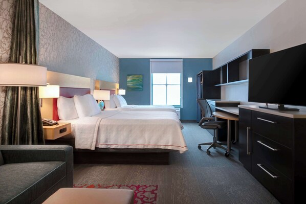 Una habitación de hotel con cama, escritorio, televisor y una silla.