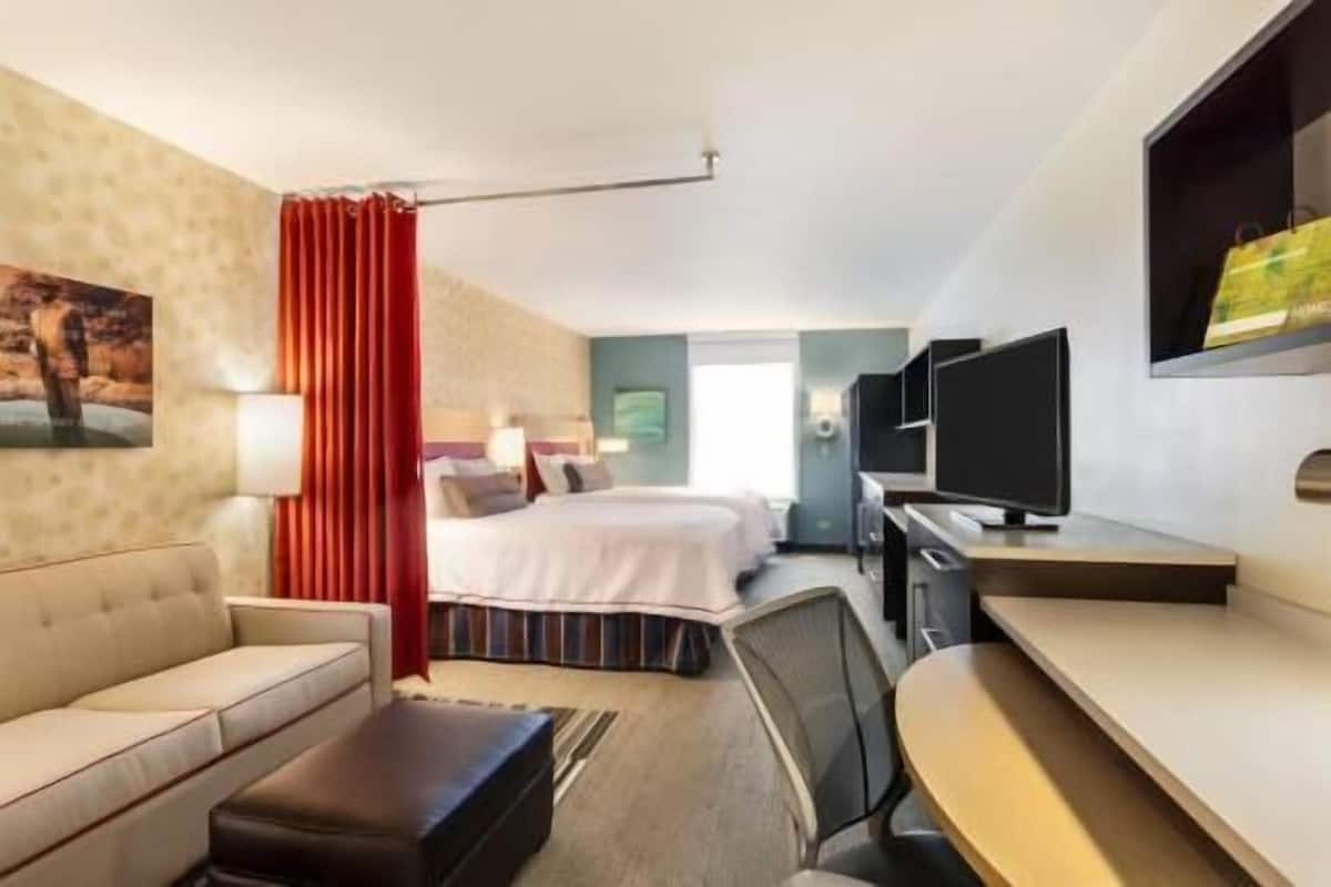 A hotel room with a bed, a desk, a TV, a sofa, and a window.