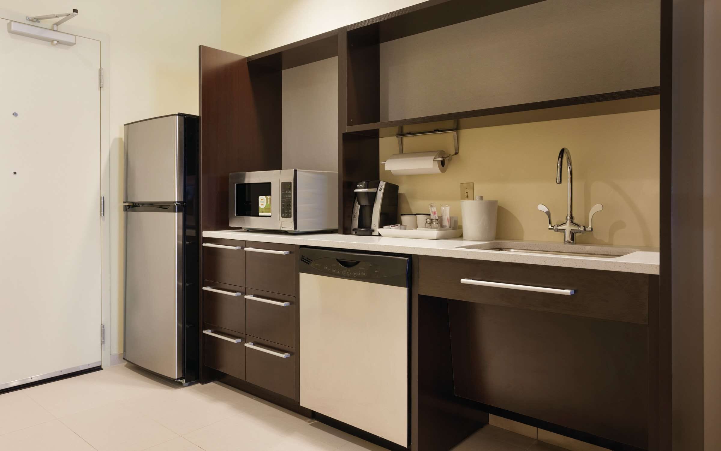 A modern kitchen with a built-in microwave, coffee maker, and a sink with a faucet.